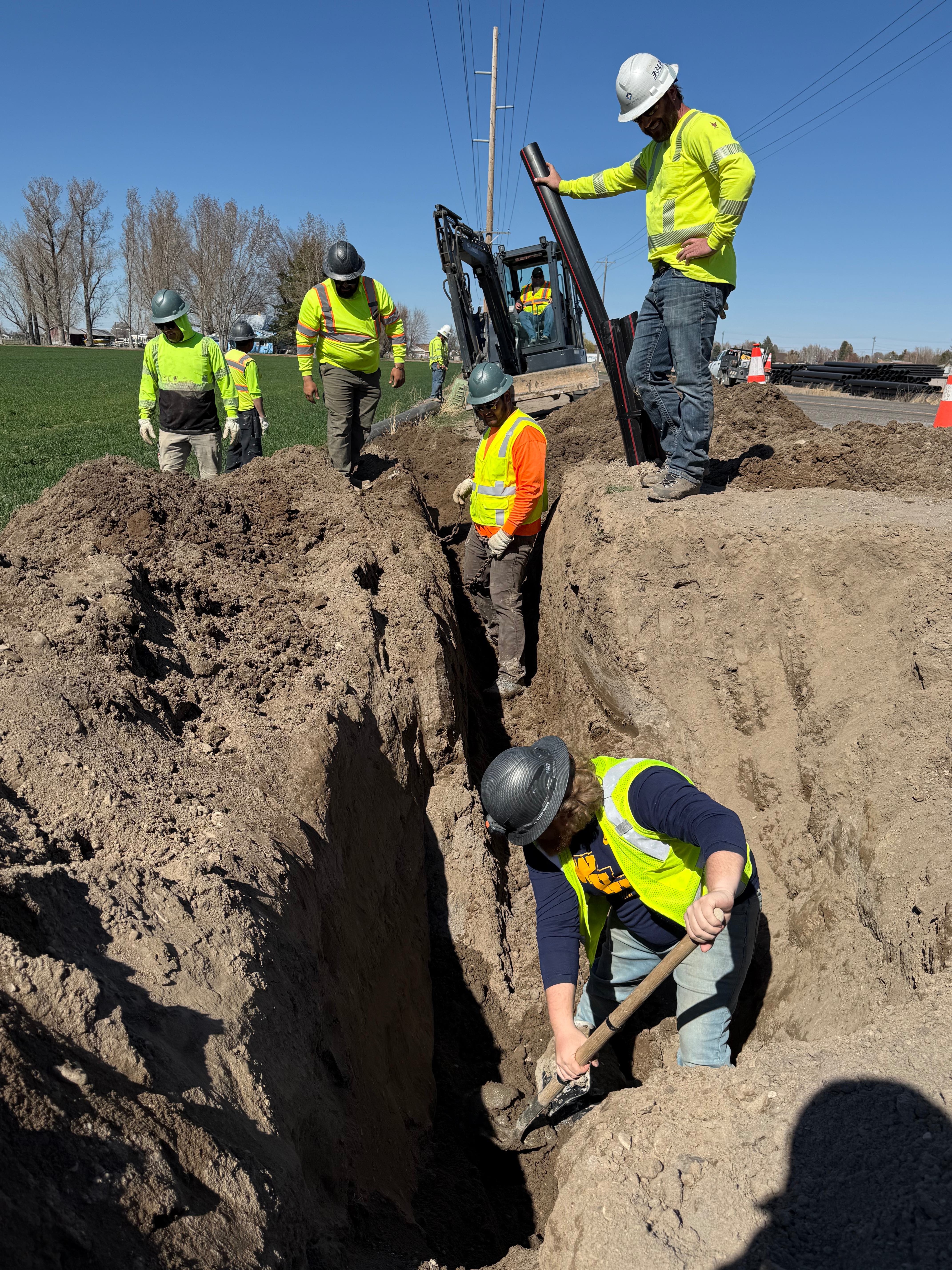 Telecom construction crew excavating utility trench with full team coordination